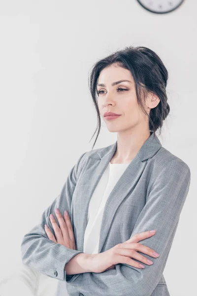 Beautiful serious businesswoman in suit with crossed arms looking away — Stock Photo