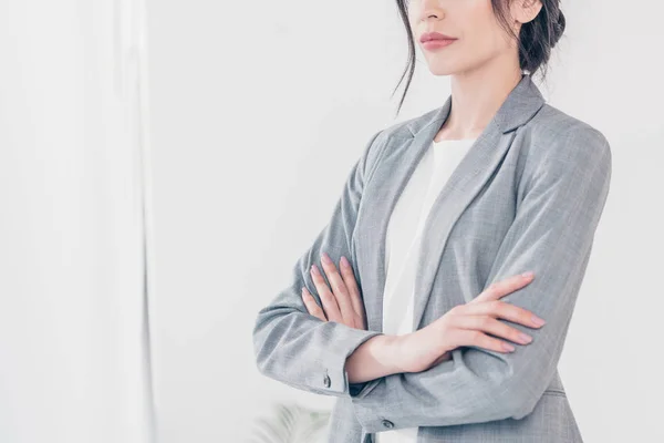 Cropped view of businesswoman in grey suit with crossed arms on white with copy space — Stock Photo