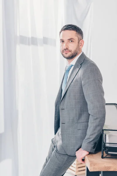 Seriöser, gutaussehender Geschäftsmann im Anzug blickt im Büro mit Kopierraum in die Kamera — Stockfoto