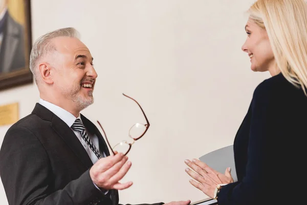 Guapo profesor mirando atractivo rubia mujer mientras sosteniendo gafas - foto de stock