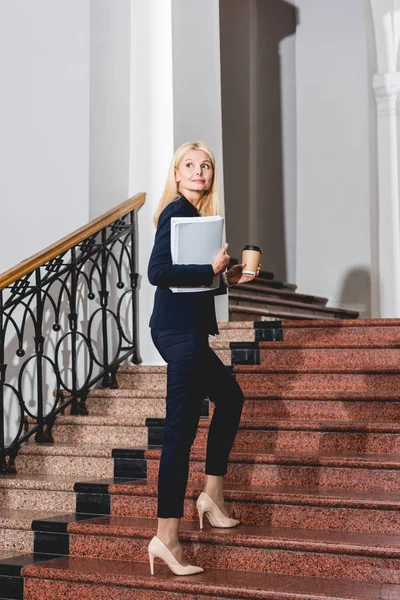 Glücklich und attraktiv blonde Lehrerin hält Ordner und Einwegbecher — Stockfoto