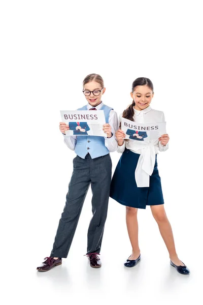 Schoolgirls in formal wear reading business newspapers On White — Stock Photo