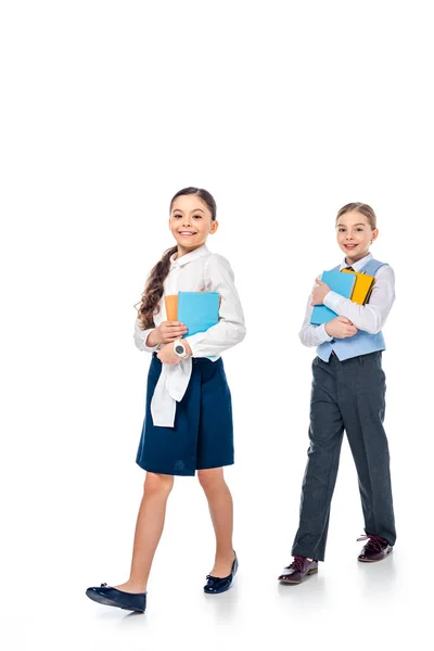 Écolières en tenue formelle tenant des livres et regardant caméra sur blanc — Photo de stock