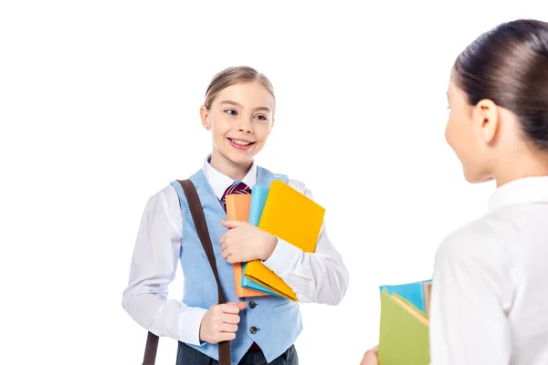 Colegialas en ropa formal con libros mirándose aisladas en blanco - foto de stock