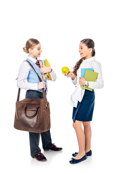 Studentesse in abito formale con libri e mela che si guardano e parlano su bianco — Foto stock