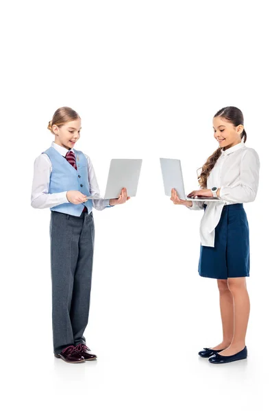 Smiling schoolgirls in formal wear using laptops On White — Stock Photo