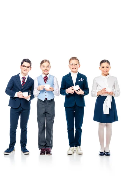 Des écoliers souriants se faisant passer pour des hommes d'affaires tenant des tasses à café et regardant la caméra On White — Photo de stock