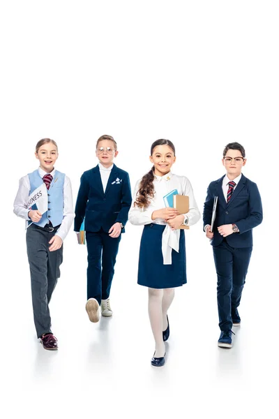 Schoolchildren pretending to be businesspeople with books and newspaper walking On White — Stock Photo