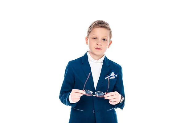 Écolier en costume d'homme d'affaires tenant des lunettes et regardant caméra isolé sur blanc — Photo de stock