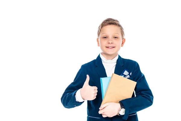 Écolier souriant montrant pouce vers le haut signe et tenant des livres isolés sur blanc — Photo de stock