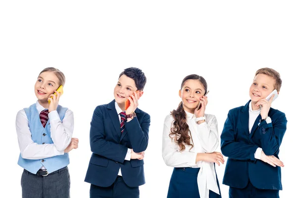 Niños de escuela felices fingiendo ser empresarios hablando en teléfonos inteligentes aislados en blanco - foto de stock