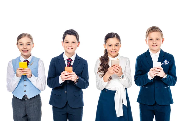Niños de escuela felices fingiendo ser empresarios usando teléfonos inteligentes aislados en blanco - foto de stock
