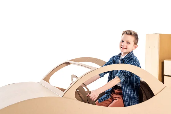 Kind sitzt im Auto aus Pappe und blickt auf Kamera isoliert auf weiß mit Kopierraum — Stockfoto
