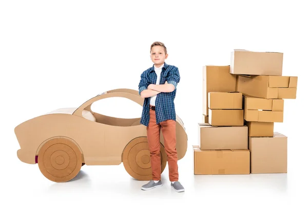 Garçon avec les bras croisés près de voiture en carton regardant caméra sur blanc — Photo de stock