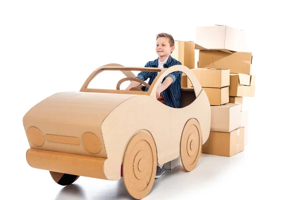 Счастливый мальчик играет с картонным автомобилем на белом — стоковое фото