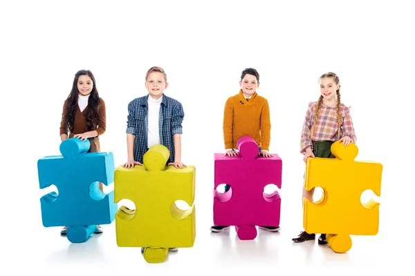 Glückliche Kinder mit Puzzleteilen, die in die Kamera auf weiß schauen — Stockfoto