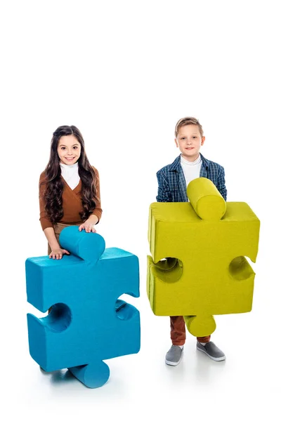 Happy kids with jigsaw puzzle pieces looking at camera on white — Stock Photo