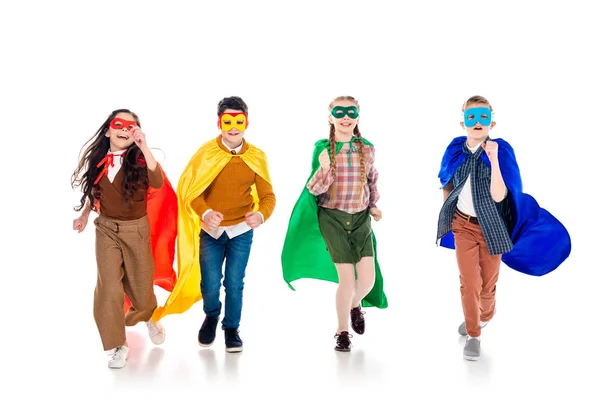 Niños felices con disfraces de superhéroes y máscaras corriendo en blanco - foto de stock