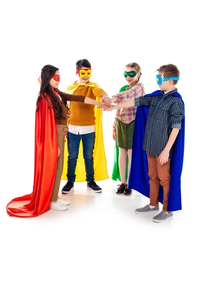 Happy kids in superhero costumes and masks Stacking Hands On White — Stock Photo