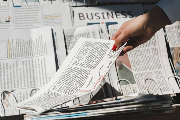 Partial view of woman taking daily print newspaper from stand — Stock Photo