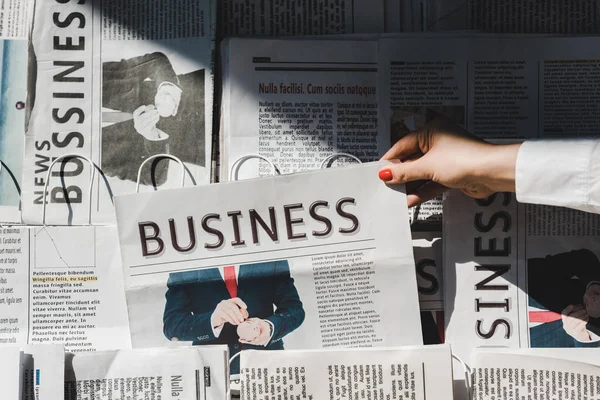 Partial view of woman taking daily print business newspaper from stand — Stock Photo