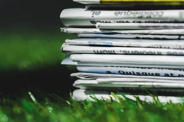 Close up de pilha de diferentes jornais impressos em grama verde fresca — Fotografia de Stock