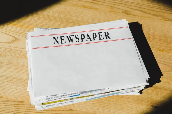 Pile of newspapers with copy space on wooden table — Stock Photo