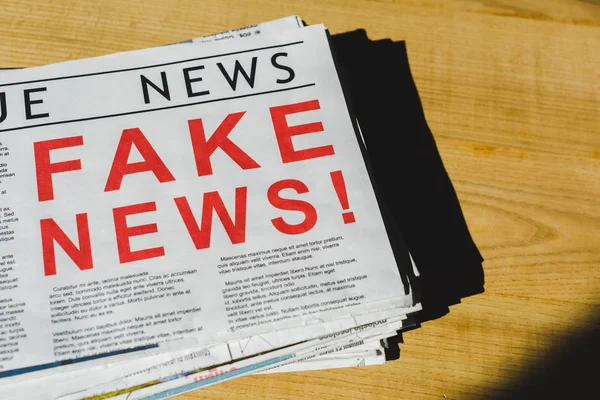 Close up of print newspaper with fake news on wooden table with shadow — Stock Photo