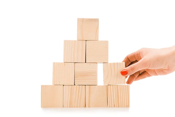 Cropped view of woman picking up one wooden block with copy space from pyramid isolated on white — Stock Photo