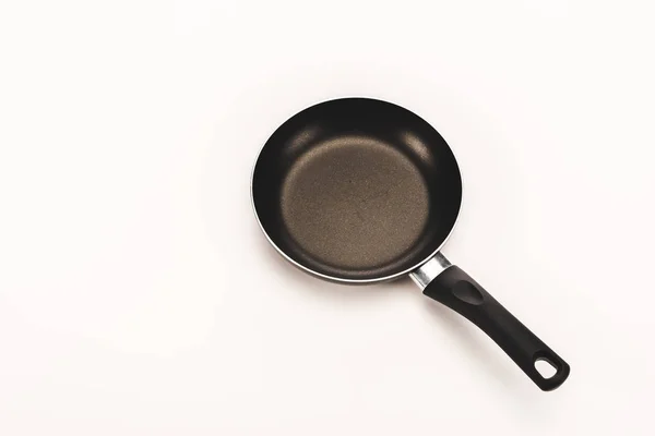 Black frying pan with handle on white background with copy space — Stock Photo
