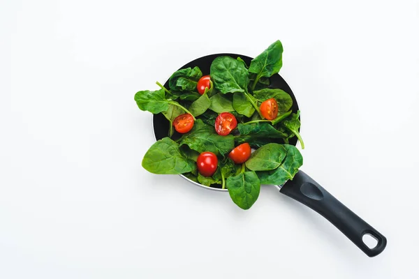 Зеленые свежие листья шпината с помидорами черри в сковороде на белом фоне — стоковое фото