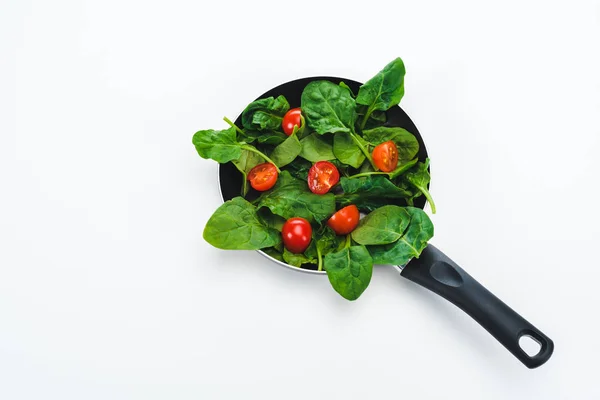 Hojas verdes de espinacas frescas con tomates cherry cur en sartén sobre fondo blanco - foto de stock