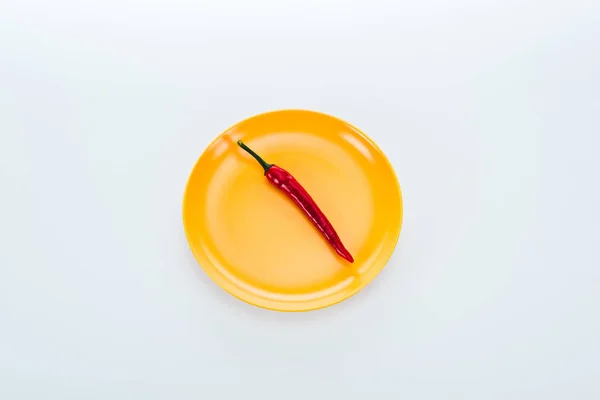 Вид сверху на красный перец чили на ярко-желтой тарелке на белом фоне — стоковое фото