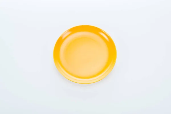 Top view of shiny empty yellow plate on white background — Stock Photo