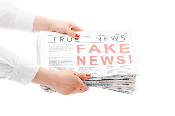 Обрізаний вид жінки, що тримає купу газет з фальшивими і справжніми новинами ізольовані на білому — стокове фото