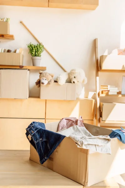 Wooden cabinets and cardboard boxes with clothes, books and toys in charity center — Stock Photo