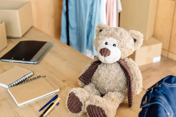 Плюшевий ведмідь, блокноти, ручки і буфер обміну на дерев'яному столі в благодійному центрі — стокове фото