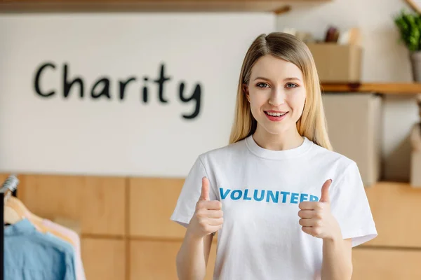 Beautiful young volunteer showing thumbs up and looking at camera — Stock Photo