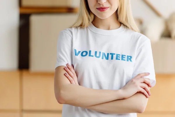 Vista cortada da menina em t-shirt branca com inscrição voluntária de pé com braços cruzados — Fotografia de Stock