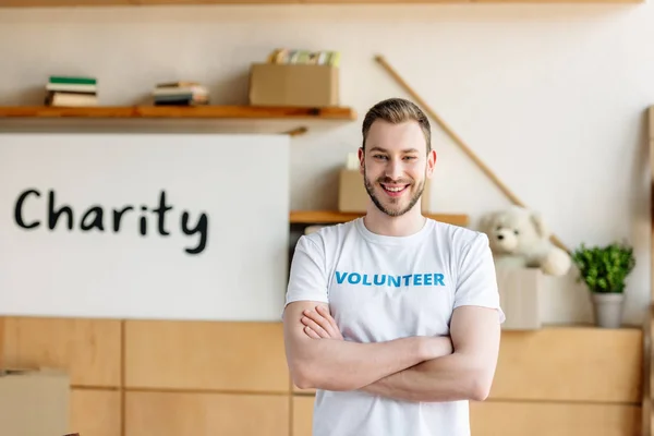 Good-looking young volunteer with crossed arms smiling and looking at camera — Stock Photo