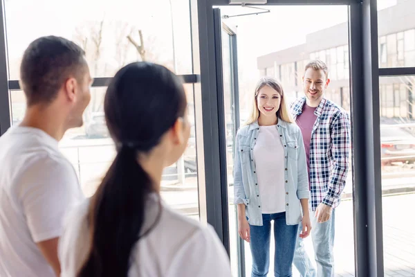 Selective focus of smiling man and pretty woman entering charity center — Stock Photo