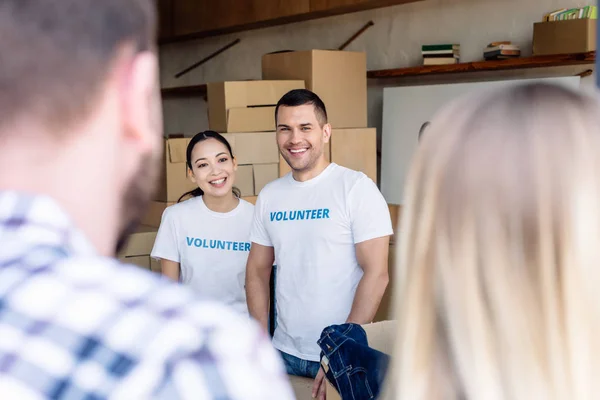 Selektiver Fokus lächelnder multikultureller Freiwilliger, die Menschen in Wohltätigkeitszentren treffen — Stockfoto