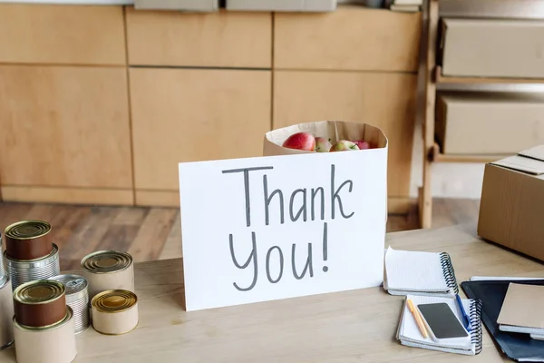 Table en bois avec boîtes, pommes dans un sac en papier, cahiers et carte avec inscription de remerciement — Photo de stock