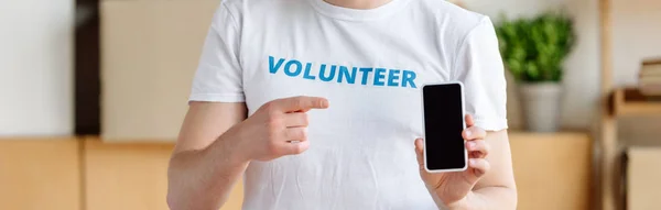 Plano panorámico de voluntariado mostrando con el dedo en el teléfono inteligente con pantalla en blanco - foto de stock