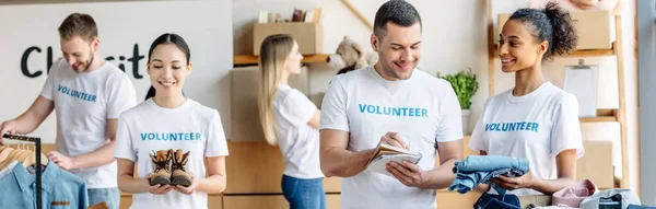 Panoramaaufnahme von fünf jungen multikulturellen Freiwilligen, die gemeinsam in einem Wohltätigkeitszentrum arbeiten — Stockfoto