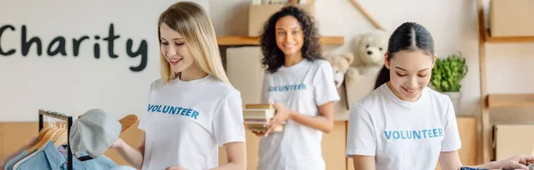 Foto panoramica di tre bellissimi volontari multiculturali che lavorano nel centro di beneficenza — Foto stock