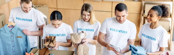 Panoramica di giovani volontari multiculturali che lavorano insieme nel centro di beneficenza — Foto stock