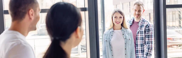 Panoramic shot of smiling man and blonde woman entering charity center — Stock Photo
