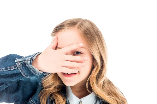 Enfant souriant en jean couvrant le visage avec la main isolée sur blanc — Photo de stock