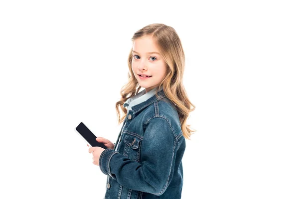 Niedliches Kind in Jeansjacke hält Smartphone mit leerem Bildschirm und schaut in Kamera isoliert auf weiß — Stockfoto